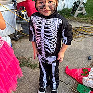 Jason joined the competition — help win amazing prizes! child, costume, skeleton, face_paint, outdoor, concrete, sidewalk, hose_reel, garden, toy, shoes, pink_tutu, dress_up, smiling, happy, playful, casual, daylight, person, yard