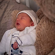Tiago participe au concours pour gagner de l'argent avec cette photo : newborn, baby, sleeping, white_hat, white_sweater, striped_clothing, teddy_bear, soft_texture, cozy, infant, portrait, cute, resting, child, bedroom, blanket, knitwear, peaceful, soft_lighting, closeup