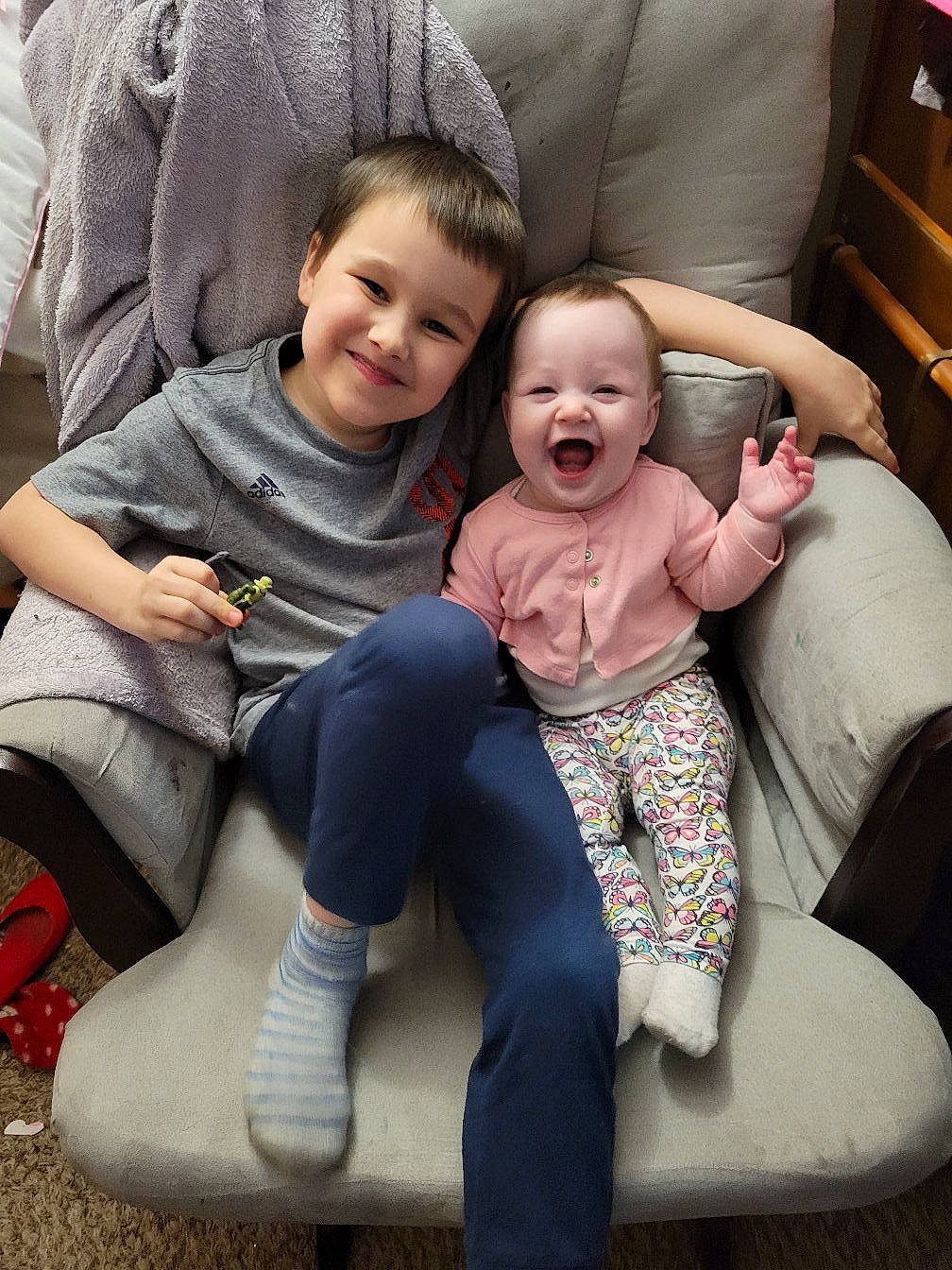 Juliet is registered to the contest to win money with this photo: baby_toddler_clothing, comfort, face, finger, fun, furniture, hair, hairstyle, happy, head, human_body, joy, knee, lap, mammal, person, product, purple, skin, smile