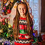 girl, child, christmas_tree, holiday_sweater, festive, ornaments, tinsel, lights, smile, long_hair, indoor, portrait, decorations, santa_figure, window, presents, red_sweater, happy, seasonal, family_photo