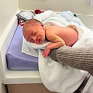 Eden a rejoint le concours — aidez-le/la à gagner de superbes lots ! newborn, baby, sleeping, towel, hand, knitted_sleeve, changing_pad, white, purple, skin, infant, resting, hospital, medical_room, peaceful, cute, child, person, newborn_baby, soft