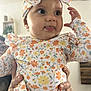 Elie participe au concours pour gagner de l'argent avec cette photo : baby, bow, candid, child, clothing, cute, expression, face, floral_outfit, hands, headband, home_decor, indoor, infant, person_holding, playful, portrait, smile, tongue_out, young_child