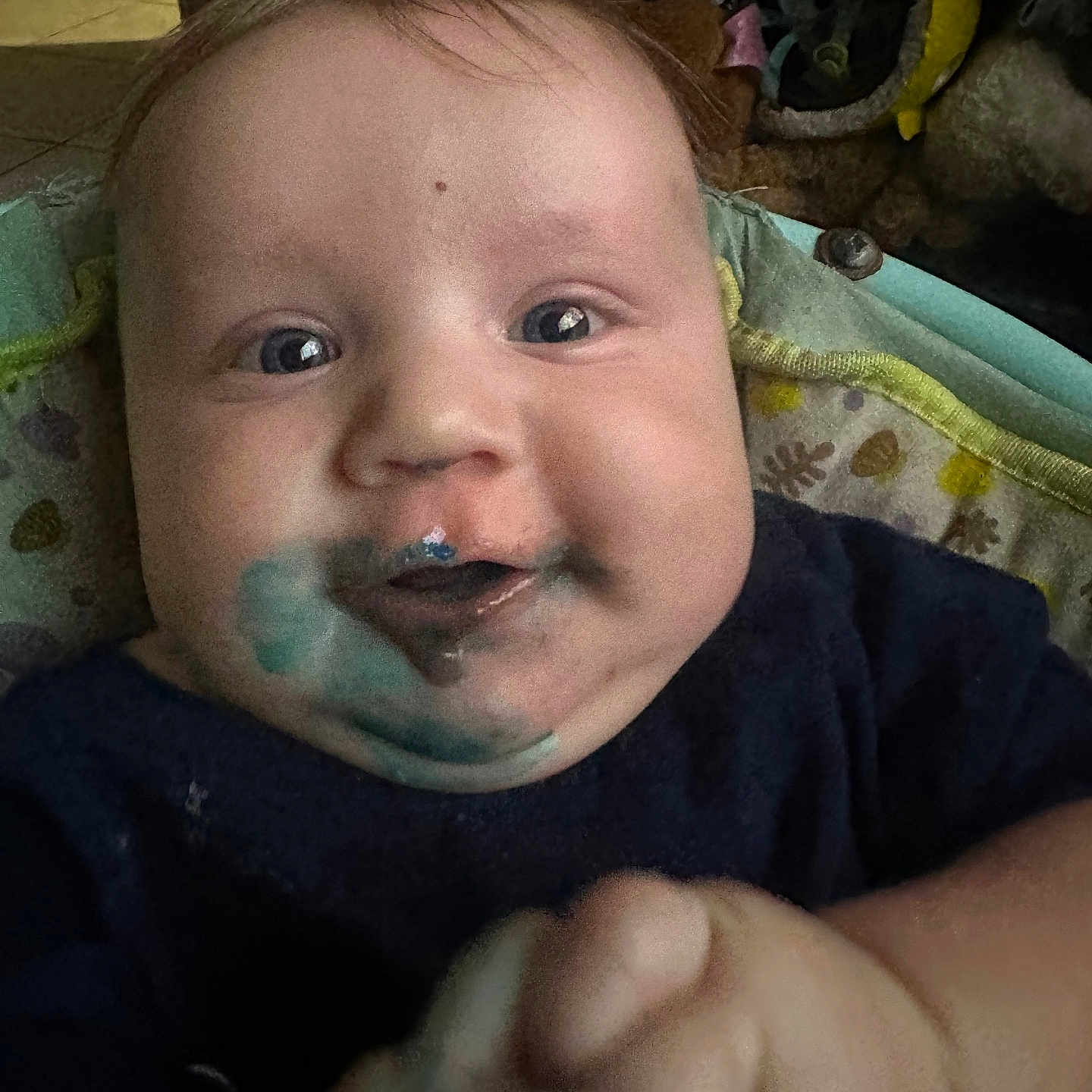 Zabel Carroll is registered to the contest to win money with this photo: baby, blue_paint, cheeks, child, closeup, clothing, cute, expression, eyes, face, hand, indoor, infant, messy, person, playful, portrait, skin, smile, young
