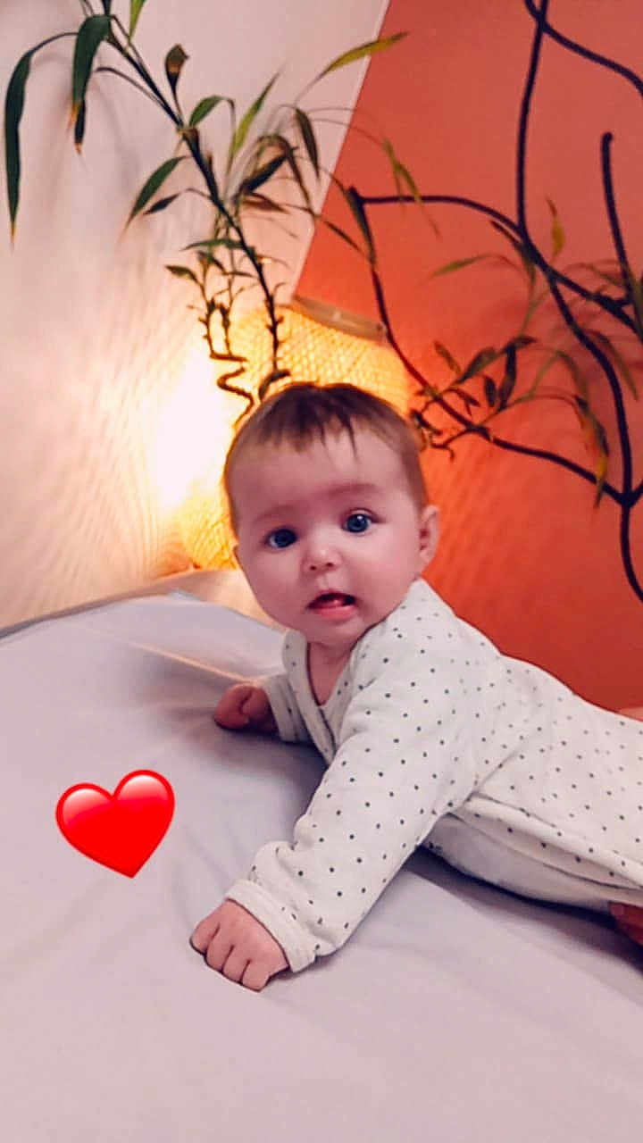 Shelsea a rejoint le concours — aidez-le/la à gagner de superbes lots ! baby, infant, bed, onesie, polka_dot, face, hand, plant, lamp, light, red_heart_emoji, indoor, curious, lying_down, skin, child, young, portrait, expression, cozy
