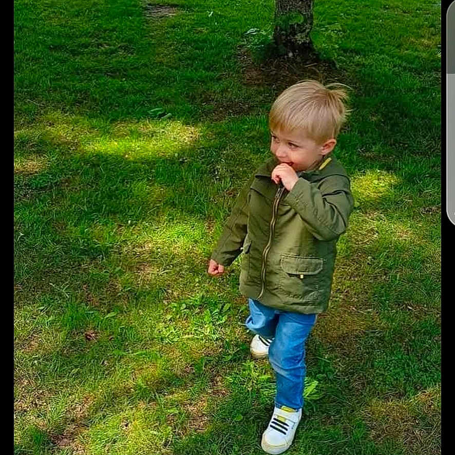 Lorenzo a rejoint le concours — aidez-le/la à gagner de superbes lots ! blond_hair, boy, casual_clothing, child, curious, daylight, grass, greenery, house, jacket, jeans, nature, outdoor, park, shoes, spring, sunlight, tree, walking, yard