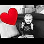 child, smile, blonde_hair, couch, leather, pillow, heart_emoji, baby_gate, staircase, black_and_white, indoor, happy, sitting, clothing, person, living_room, home, casual, playful, young