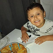 Alessio participe au concours pour gagner de l'argent avec cette photo : child, boy, smiling, table, pie, candles, birthday, spoon, napkin, plate, indoor, celebration, food, dessert, happy, face, sitting, short_hair, casual_clothing, party