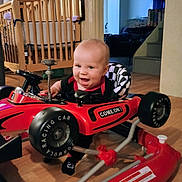 Aviel joined the competition — help win amazing prizes! baby, black_clothing, checkered_pattern, child, crib, cute, floor, furniture, happy, indoor, living_room, person, playtime, racing_car, red_toy, smiling, stairs, toy, walker, wooden_floor