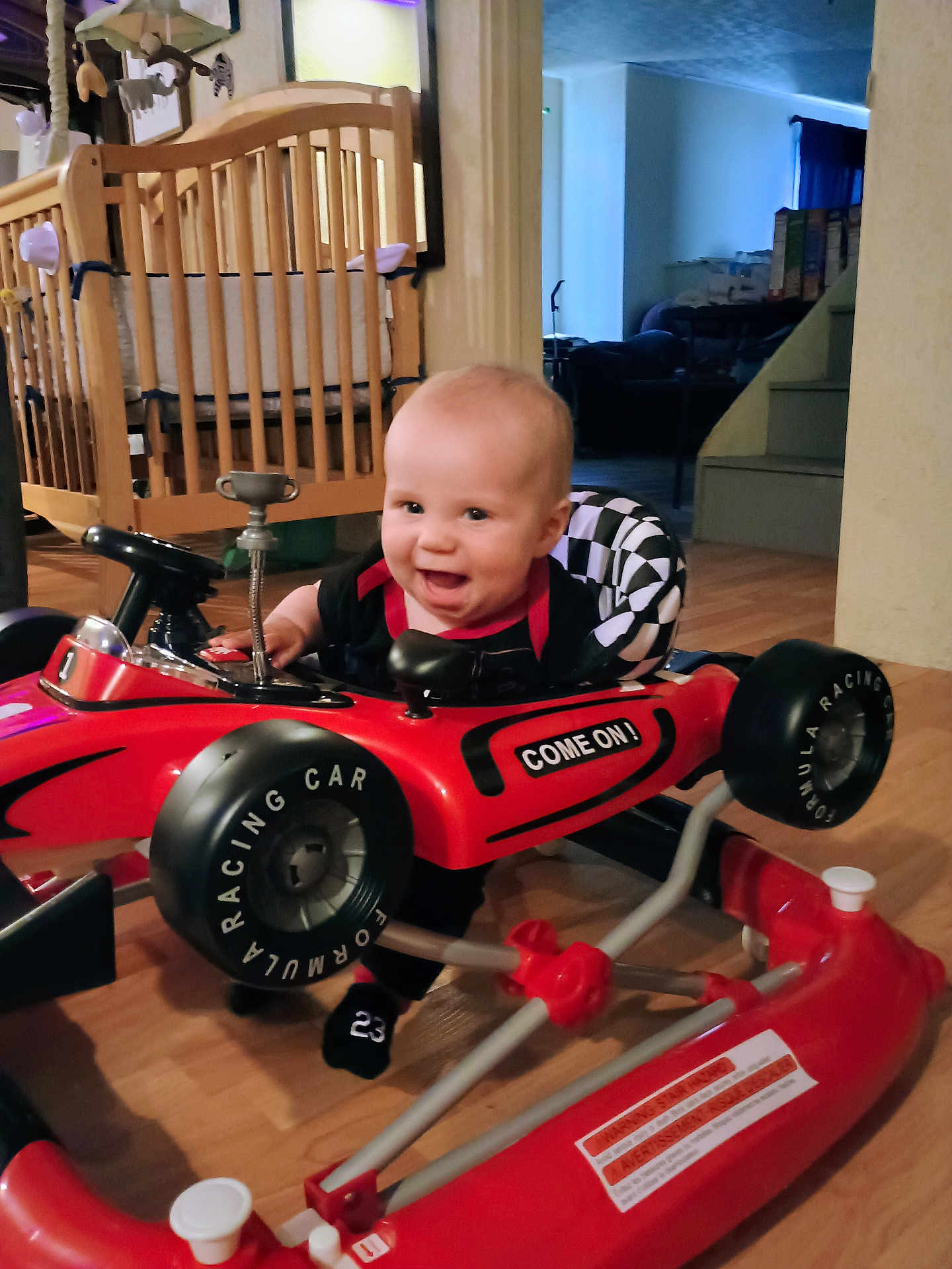 Aviel joined the competition — help win amazing prizes! baby, black_clothing, checkered_pattern, child, crib, cute, floor, furniture, happy, indoor, living_room, person, playtime, racing_car, red_toy, smiling, stairs, toy, walker, wooden_floor