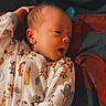 newborn, baby, infant, sleepwear, animal_print, blanket, lying_down, hand, face, portrait, cute, child, soft_lighting, indoors, fabric, pattern, blue, red, cozy, resting
