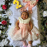 Janelle joined the competition — help win amazing prizes! baby, smiling, dress, pink, white, lace, headband, flower, floral_wreath, number_two, celebration, socks, happy, infant, cute, portrait, laying_down, decor, greenery, indoors