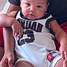 adult, baby, basketball_jersey, bed, child, close_up, curious, curly_hair, family, hands, held, indoors, infant, number_23, photography, portrait, safe, sitting, smiling, sportswear