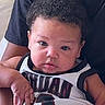 Lionel joined the competition — help win amazing prizes! arm, baby, basketball_jersey, black_and_white, child, close_up, clothing, curly_hair, face, hand, held, indoor, infant, person, photography, portrait, serious_expression, sitting, sportswear, wide_eyes
