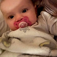 Camilla is registered to the contest to win money with this photo: baby, blanket, child, closeup, comfort, cozy, cute, expression, eyes, face, head, indoors, infant, pacifier, person, sleepwear, soft, warm, wrapped, young