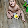 Alexia is registered to the contest to win money with this photo: barefoot, bowl, child, cute, diaper, expression, floor, food, fork, happy, indoor, kitchen, mealtime, person, playful, sitting, smile, toddler, wooden_floor, young_child