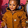 Mylah joined the competition — help win amazing prizes! toddler, child, smile, brown_jacket, braided_hair, beads, purse, pink, festive, red_background, golden_furniture, portrait, cute, fashion, young_child, accessory, happy, indoor, person, jacket