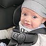 baby, infant, car_seat, car_safety_harness, gray_hat, blue_eyes, cute, child, young, clothing, seatbelt, car_interior, portrait, smile, expression, sitting, close_up, person, cute_face, infant_clothes