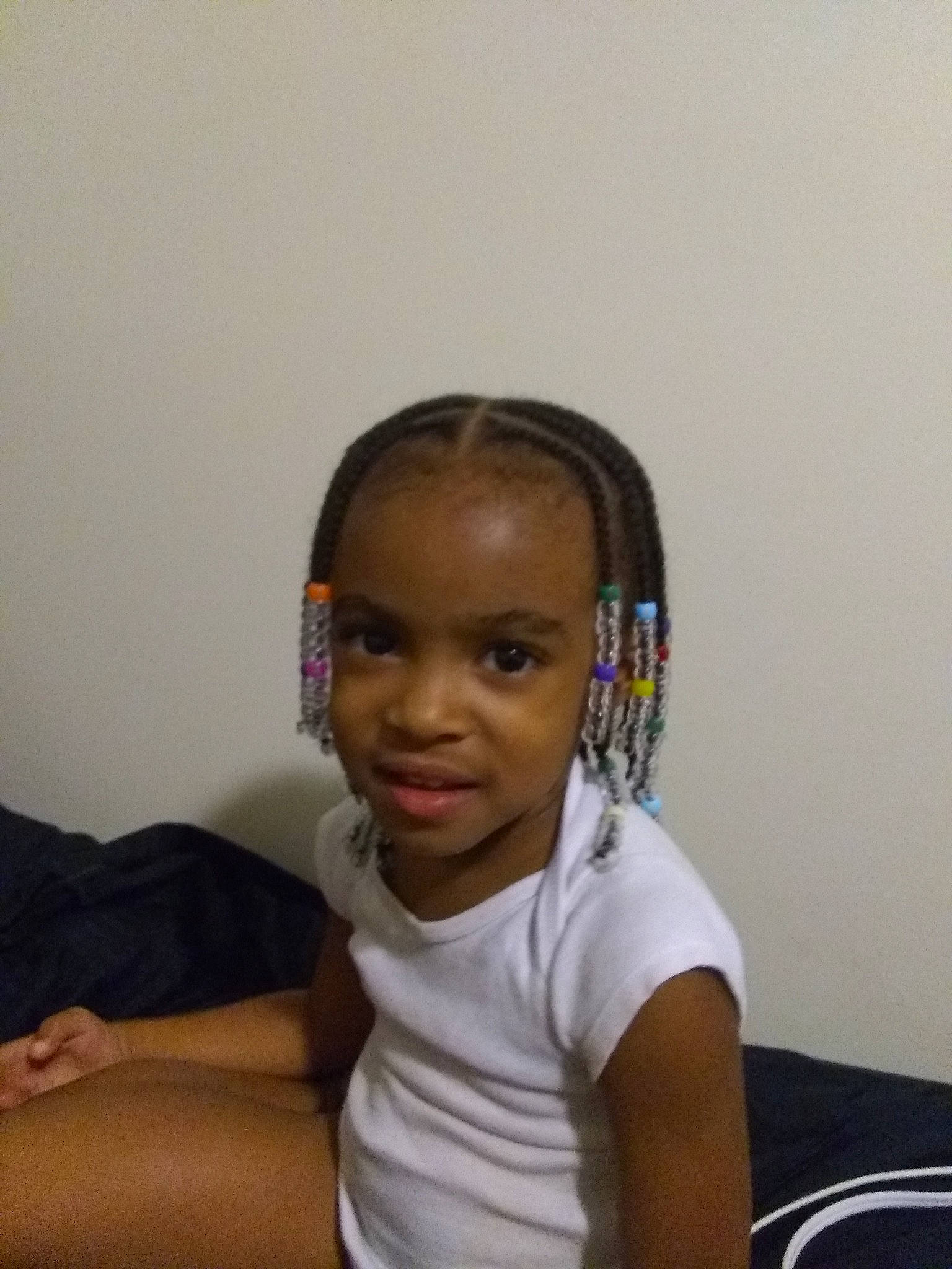 Nori is registered to the contest to win money with this photo: arm, black_hair, cheek, child, cornrows, ear, forehead, hair, hair_accessory, hairstyle, head, neck, person, sitting, toddler