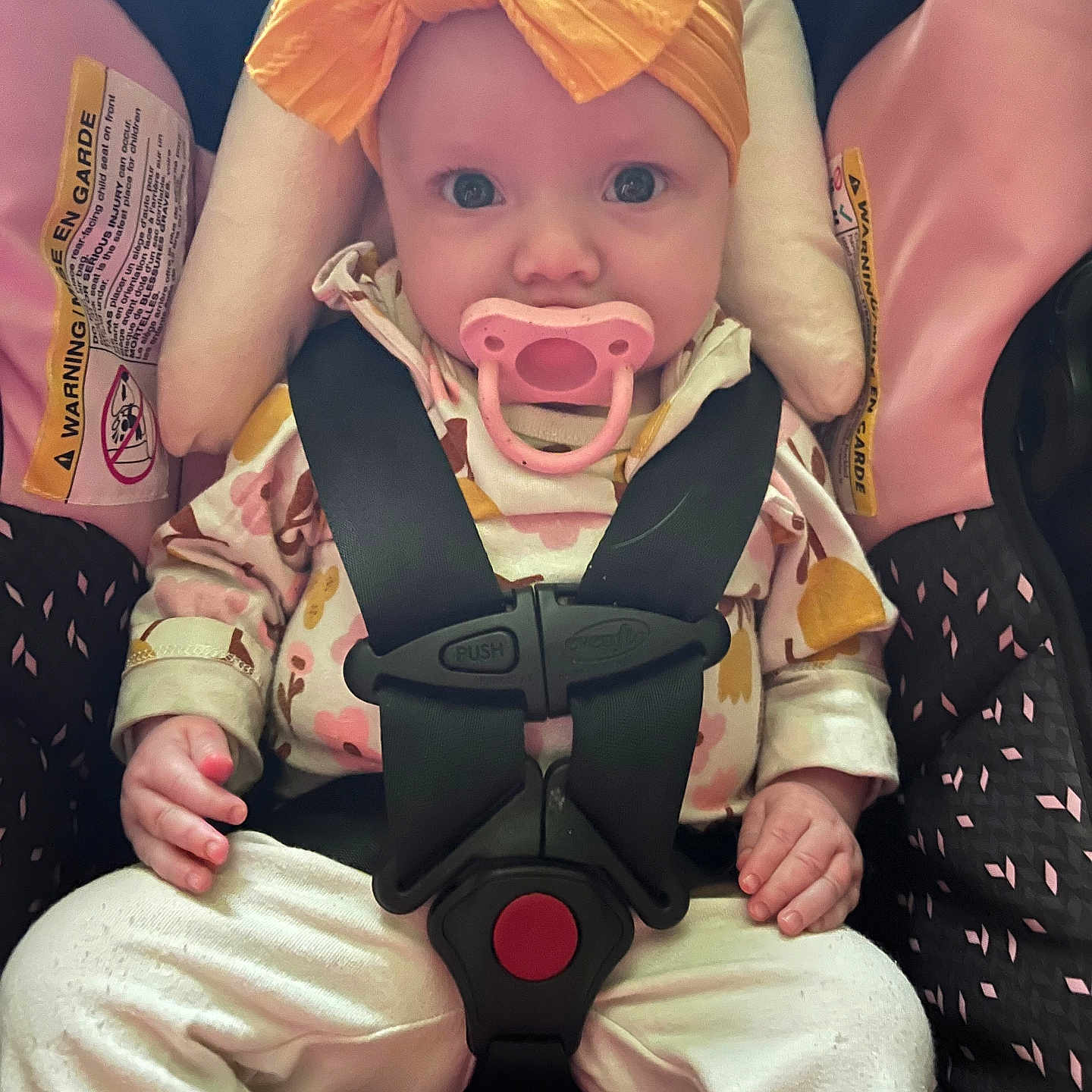 Drew joined the competition — help win amazing prizes! baby, car_seat, child, child_safety, clothing, curious, cute, face, hands, headwear, indoor, infant, pacifier, pink, portrait, seatbelt, sitting, straps, white_pants, yellow_bow