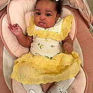 Jaylah joined the competition — help win amazing prizes! baby, child, infant, girl, curly_hair, yellow_dress, white_bows, socks, sneakers, baby_seat, pink_cushion, cute, playful, tongue_out, portrait, indoors, comfortable, happy, small_hands, soft_fabric