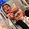 baby, black_socks, child, clapping, clothing, curly_hair, cute, expression, face, happy, high_chair, home, indoor, infant, joyful, peach_shirt, person, seat, smiling, toddler