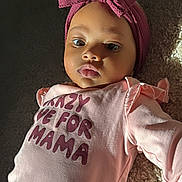 Kylie joined the competition — help win amazing prizes! baby, infant, child, headband, pink_clothing, onesie, text_on_clothing, carpet, sunlight, portrait, face, cute, indoor, soft_light, lying_down, chubby_cheeks, expression, young_child, apparel, human