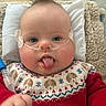 Truman is registered to the contest to win money with this photo: baby, infant, face, tongue, sweater, red_clothing, patterned_clothing, nasal_cannula, medical_tube, pillow, blanket, hand, blue_eyes, indoor, cute, chubby_cheeks, expression, lying_down, closeup, texture
