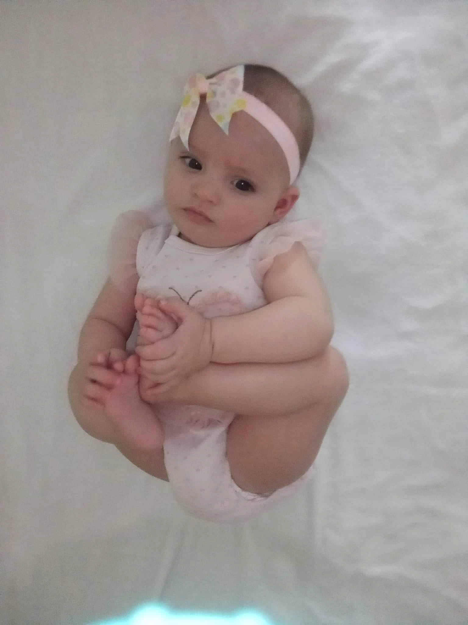 Olive is registered to the contest to win money with this photo: baby, baby_products, baby_toddler_clothing, cap, chest, comfort, eye, foot, gesture, hand, headband, headpiece, headwear, human_leg, iris, lip, person, stomach, thigh, thumb