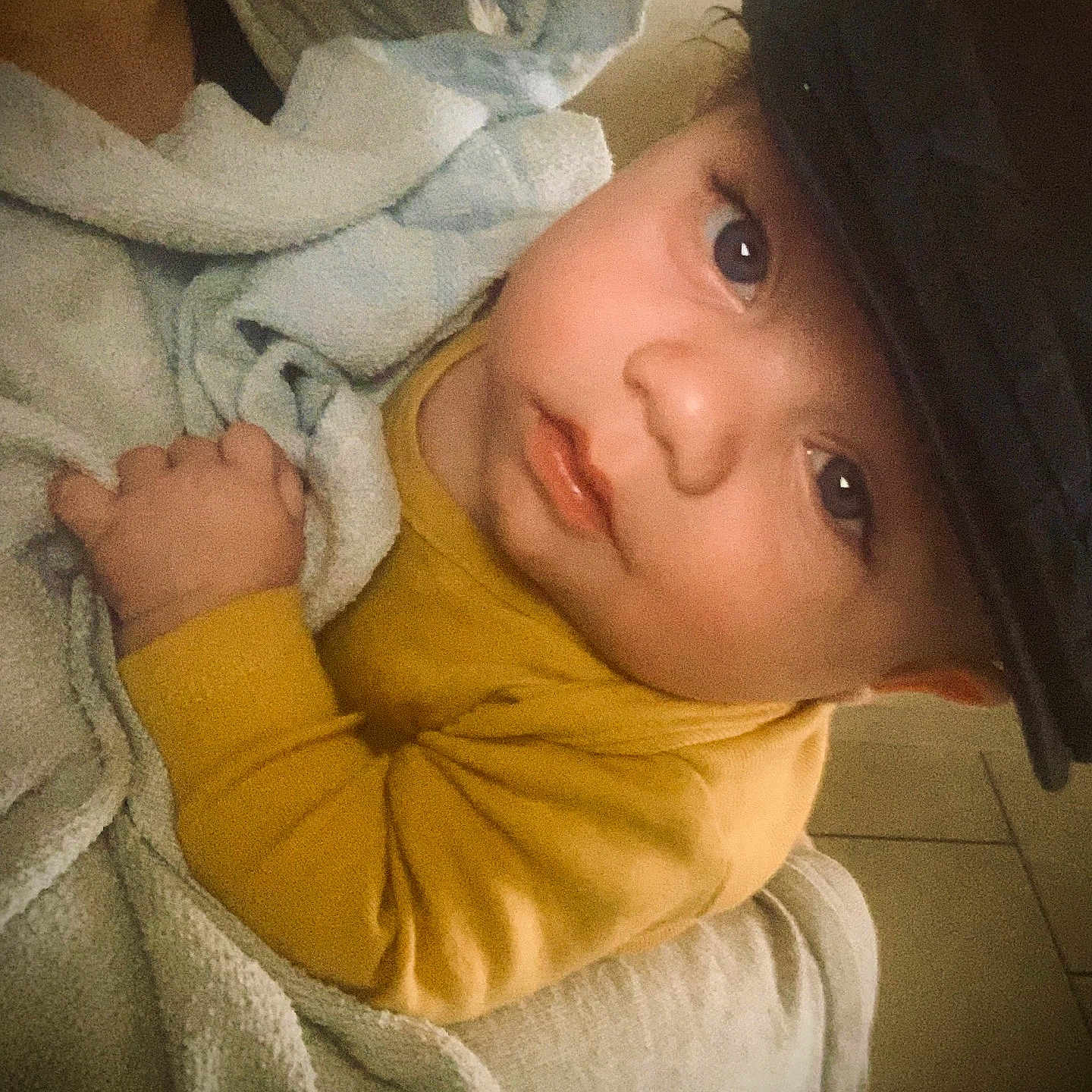 Adan participe au concours pour gagner de l'argent avec cette photo : baby, child, blanket, cap, yellow_clothing, cute, indoors, portrait, face, hand, soft_texture, warm, cozy, looking, infant, person, young, expression, sleepwear, resting