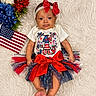 baby, infant, tutu, red_bow, headband, american_flag, flowers, white_rug, patriotic, 4th_of_july, cute, festive, clothing, portrait, smiling, celebration, holiday, toddler, lying_down, indoor