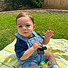 toddler, child, outdoor, grass, blanket, toy, denim_overalls, blue_shirt, sock, sunlight, backyard, fence, greenery, playing, person, cute, baby, sitting, happy, summer