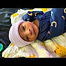 baby, infant, child, portrait, lying_down, blanket, knit_hat, winter_clothing, navy_outfit, striped_hat, duck_pattern, bed, indoor, face, eyes, looking_at_camera, calm, cute, textile, photography
