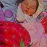 Izabelle is registered to the contest to win money with this photo: baby, newborn, sleeping, infant, child, face, portrait, indoors, blanket, bed, colorful, floral, strawberry, cartoon, pink, white_clothing, lying_down, peaceful, cozy, photography