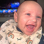 Liandro participe au concours pour gagner de l'argent avec cette photo : baby, bib, blue_eyes, bunny_pattern, cheeks, child, closeup, cute, face, flash, happy, indoor, infant, joyful, mouth_open, person, rainbow_pattern, skin, smiling, television