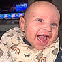 baby, bib, blue_eyes, bunny_pattern, cheeks, child, closeup, cute, face, flash, happy, indoor, infant, joyful, mouth_open, person, rainbow_pattern, skin, smiling, television