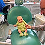 Oscar joined the competition — help win amazing prizes! baby, child, dental_chair, tattoo, adult_hand, clinic, medical_equipment, sink, window, floor, cabinet, person, green_clothing, socks, expression, holding_hand, indoor, light, curious, healthcare