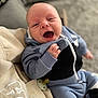Oscar joined the competition — help win amazing prizes! baby, infant, smiling, happy, blue_hoodie, pacifier, hand, face, clothing, person, indoor, couch, blanket, comfort, cute, joy, hood, sitting, young_child, portrait