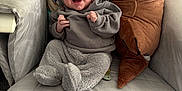 Oscar is registered to the contest to win money with this photo: baby, infant, smiling, sitting, armchair, plush_toy, dinosaur, clothing, hoodie, cozy, furniture, indoor, child, cute, soft, pillow, happy, person, young, comfort