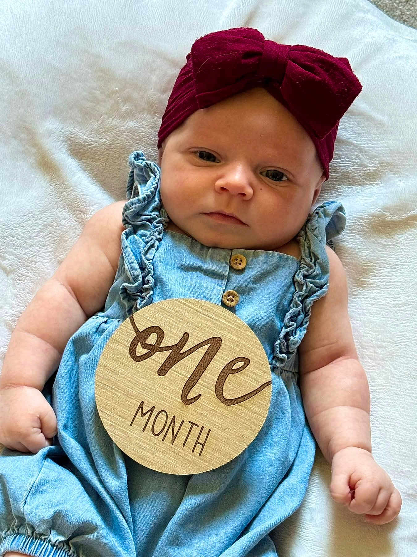 Ella joined the competition — help win amazing prizes! baby, infant, one_month, headband, bow, denim, romper, wooden_sign, sign, milestone, blanket, soft_texture, baby_clothes, cute, portrait, lying_down, skin, hand, face, newborn