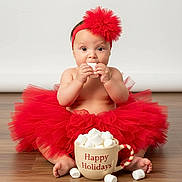 Claudia is registered to the contest to win money with this photo: accessory, baby, celebration, child, cup, cute, festive, floor, food, headwear, holiday, holiday_season, indoor, marshmallows, portrait, red_headband, sitting, smiling, toddler, tutu