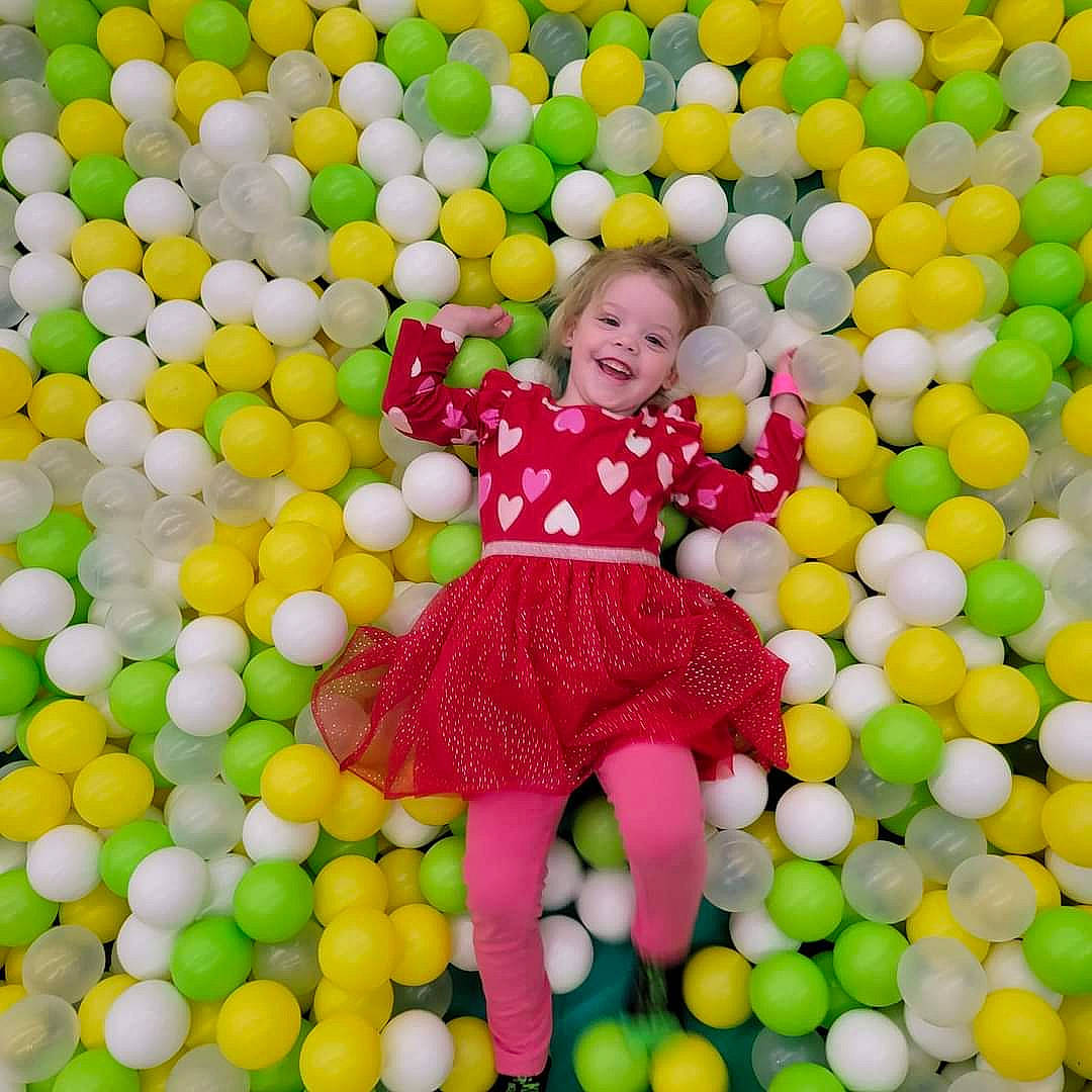 Viviana is registered to the contest to win money with this photo: baby_toddler_clothing, ball_pit, child, event, facial_expression, fun, happy, joy, leisure, magenta, pattern, people_in_nature, person, play, playground, smile, sweetness, toddler