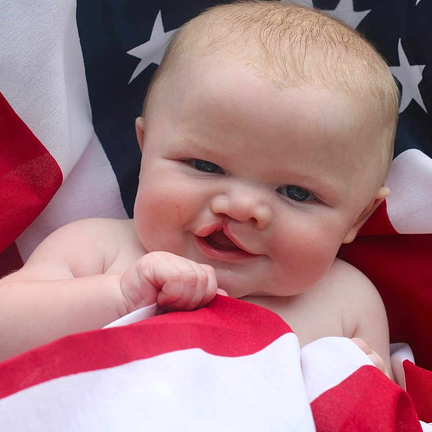 Stetson is registered to the contest to win money with this photo: accessories, americanflag, baby, bodypart, clothing, dress, face, flag, formalwear, happy, head, laughing, mouth, newborn, person, photography, portrait, smile, suit, teeth