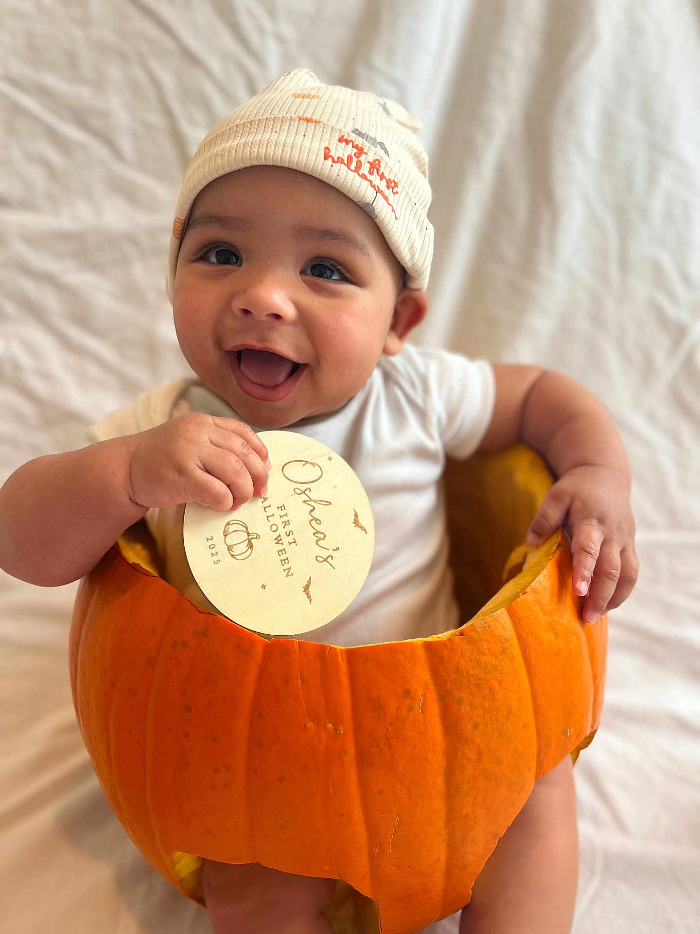 Oshea joined the competition — help win amazing prizes! baby, pumpkin, hat, smile, child, halloween, orange, cute, sign, white_clothing, happy, portrait, indoor, celebration, holiday, infant, sitting, hands, face, background