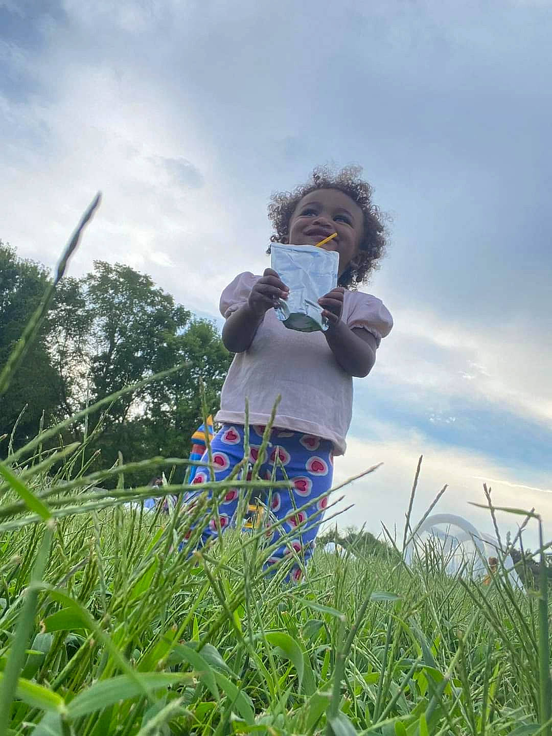 Ensley is registered to the contest to win money with this photo: agriculture, cloud, electric_blue, eyewear, field, fun, grass, grass_family, grassland, happy, human_leg, landscape, leisure, meadow, people_in_nature, person, plant, prairie, sky, toddler