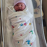Madeline is registered to the contest to win money with this photo: newborn, baby, hospital, blanket, hat, bassinet, sleeping, infant, wrapped, towel, cute, peaceful, child, bed, portrait, person, indoor, healthcare, resting, cozy