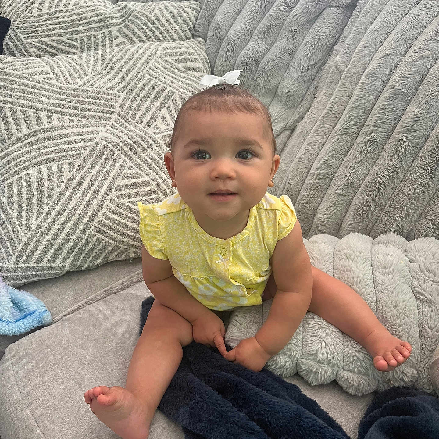Nova is registered to the contest to win money with this photo: baby, blanket, child, comfortable, cozy, cushion, cute, face, feet, girl, hands, happy, indoor, plush, portrait, sitting, smiling, sofa, white_bow, yellow_clothing