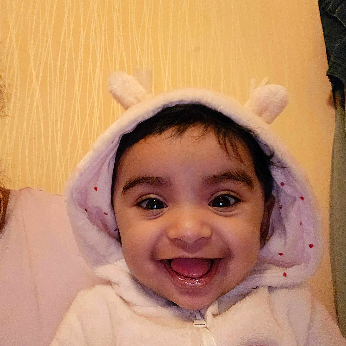 Emiliya is registered to the contest to win money with this photo: apparel, baby, child, closeup, cute, ears, expression, face, happy, hoodie, human, indoor, infant, joyful, person, portrait, smile, soft_texture, warm_lighting, young_child