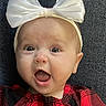 apparel, baby, bow, child, closeup, cute, expression, fabric, face, happy, headband, indoors, infant, person, plaid, portrait, red_clothing, smiling, textile, young