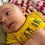 baby, infant, yellow_shirt, blanket, heart_pattern, close_up, face, arm, cute, indoor, soft_lighting, child, person, laying_down, expression, clothing, skin, young, portrait, adorable