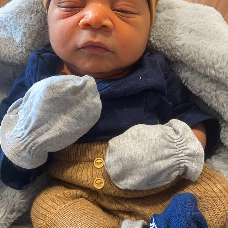 Trashun is registered to the contest to win money with this photo: baby, blanket, closeup, clothing, cozy, cute, floor, hands, hat, indoor, infant, knitwear, mittens, newborn, person, portrait, resting, sleeping, sock, warm